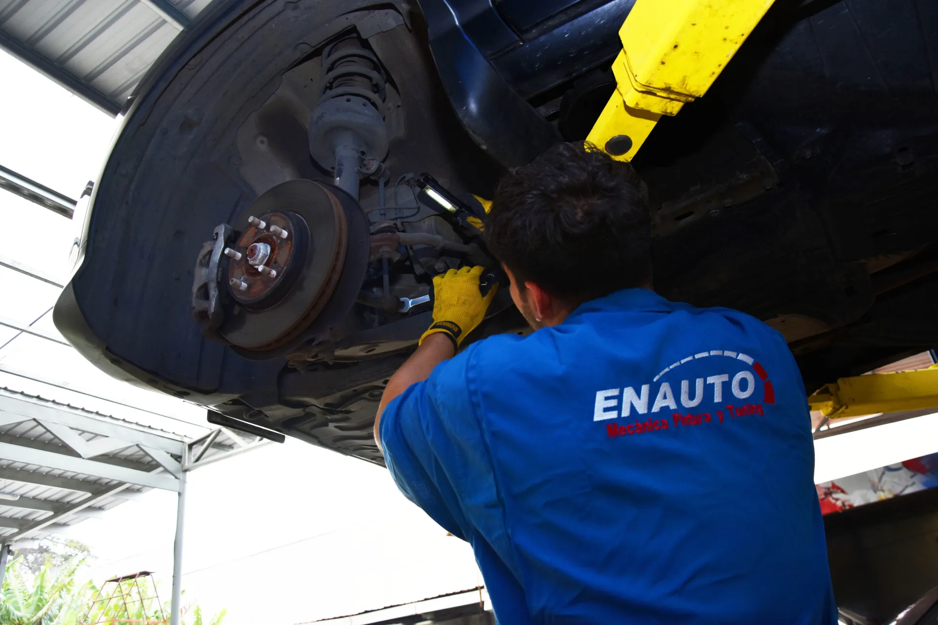 Mecánico de ENAUTO trabajando bajo un vehículo